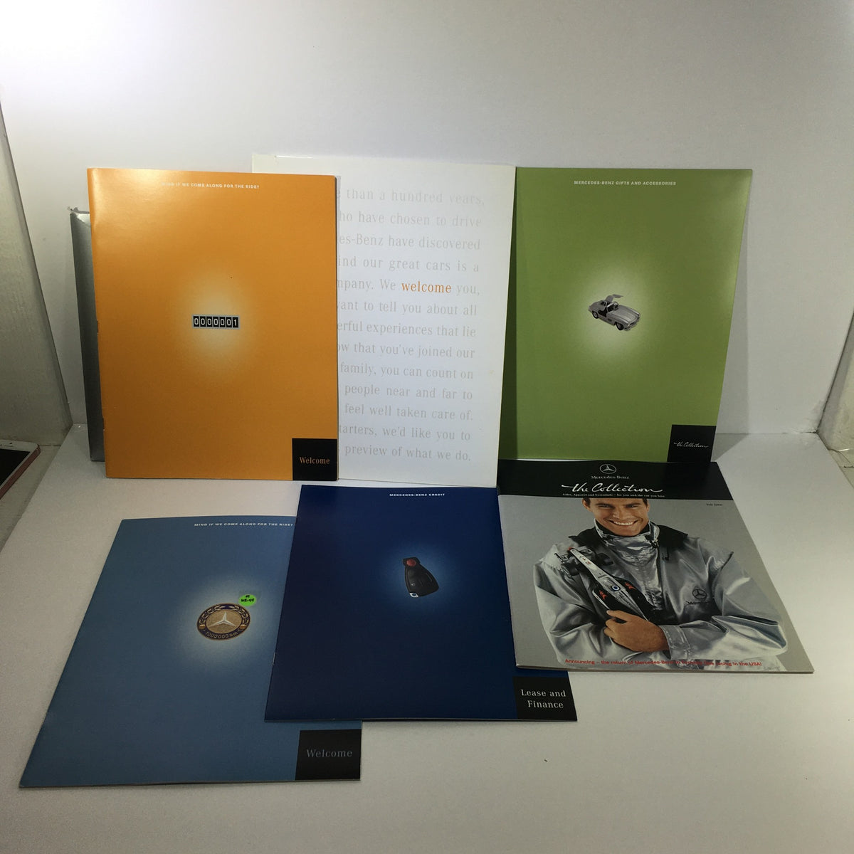 2000 Mercedes-Benz Welcome Lease and Finance The Collection Dealership Catalog showcasing various catalog covers including an orange design and images depicting automotive themes.
