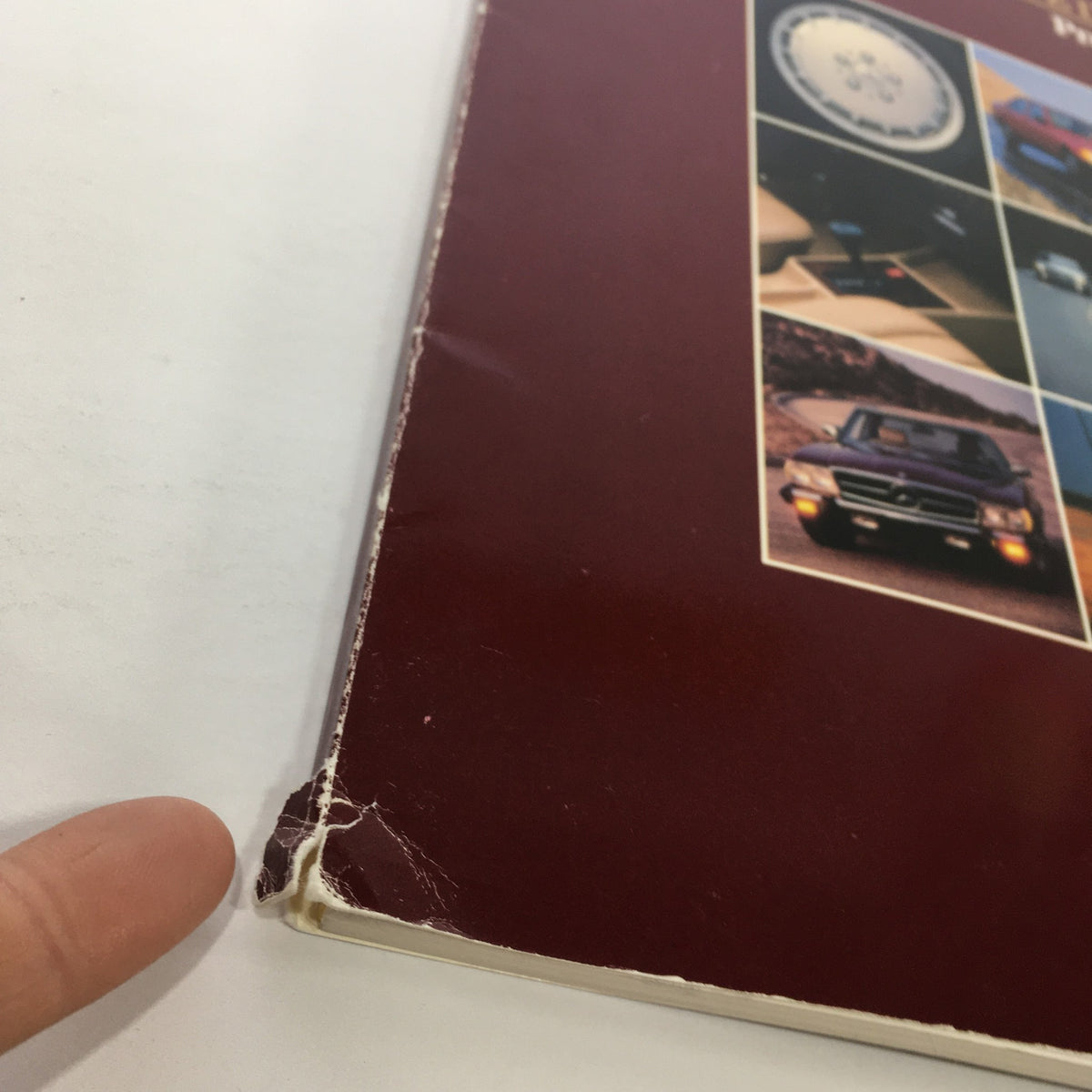 Close-up of the damaged edge of the 1984 Mercedes-Benz 190-Class Product and Sales Information Catalog, showing wear and tear.