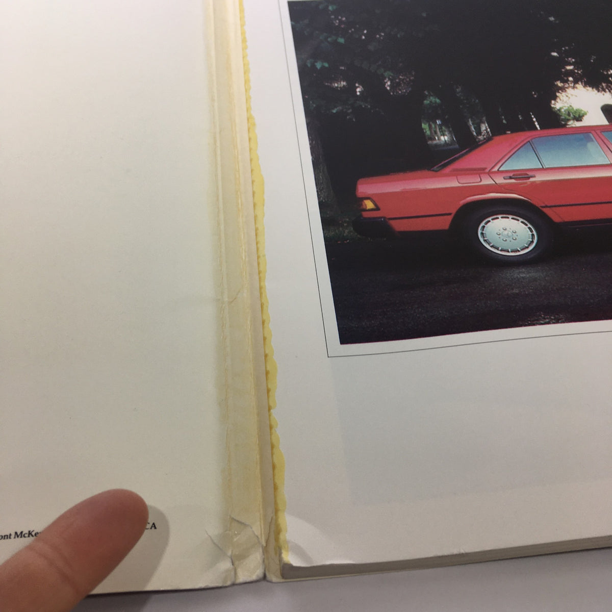 Interior view of the 1984 Mercedes-Benz 190-Class Product and Sales Information Catalog with a yellowing page and a photograph of a red Mercedes vehicle.