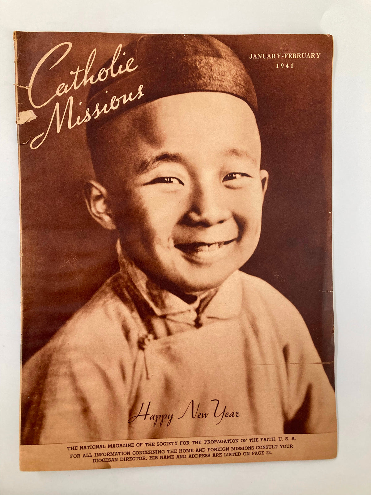 Cover of VTG Catholic Missions January February 1941 magazine, featuring a smiling young boy in traditional attire and the text 'Happy New Year'. This vintage publication showcases the Catholic Church's mission work.