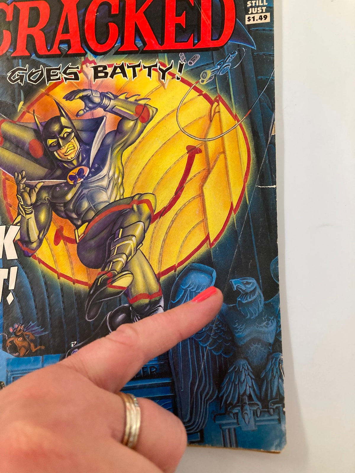 Close-up view of Cracked Humor Magazine October 1989 cover highlighting The Dark Knight's illustration, with a finger pointing at detail.