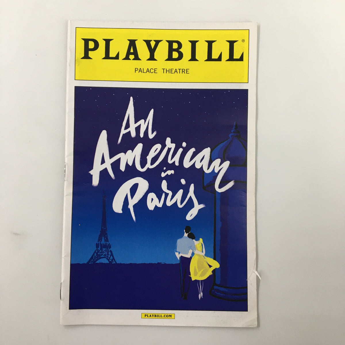 2015 Playbill for An American in Paris, featuring a vibrant cover design with a couple silhouetted against a blue background and the Eiffel Tower.