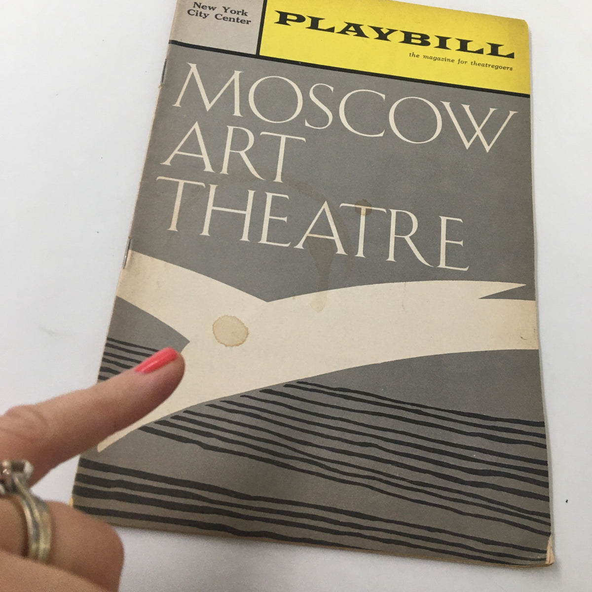 Close-up view of the 1965 Playbill for The Cherry Orchard by Moscow Art Theatre, highlighting the cover with slight wear and a pointing finger.