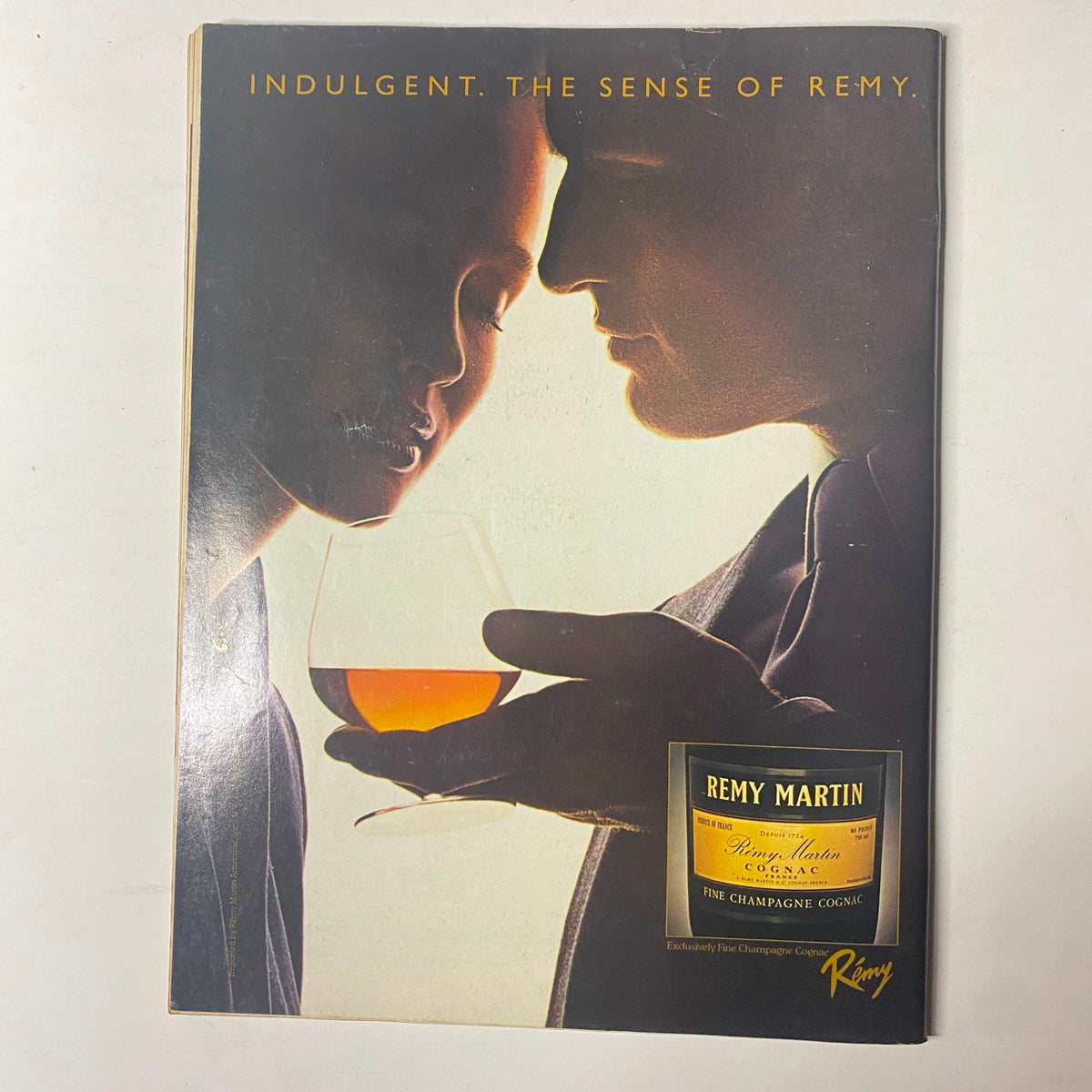 Back cover of a magazine featuring an advertisement for Remy Martin, with an elegant portrayal of a couple enjoying cognac.