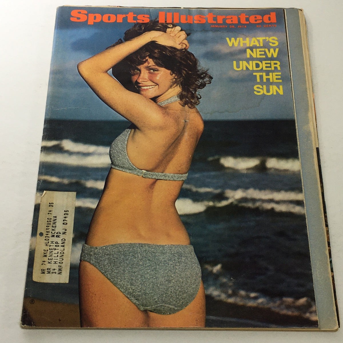 Cover image of Sports Illustrated dated January 28, 1974, featuring a woman in a bikini at the beach with the caption 'What's New Under The Sun.' The magazine showcases a retro aesthetic with a vibrant color palette.