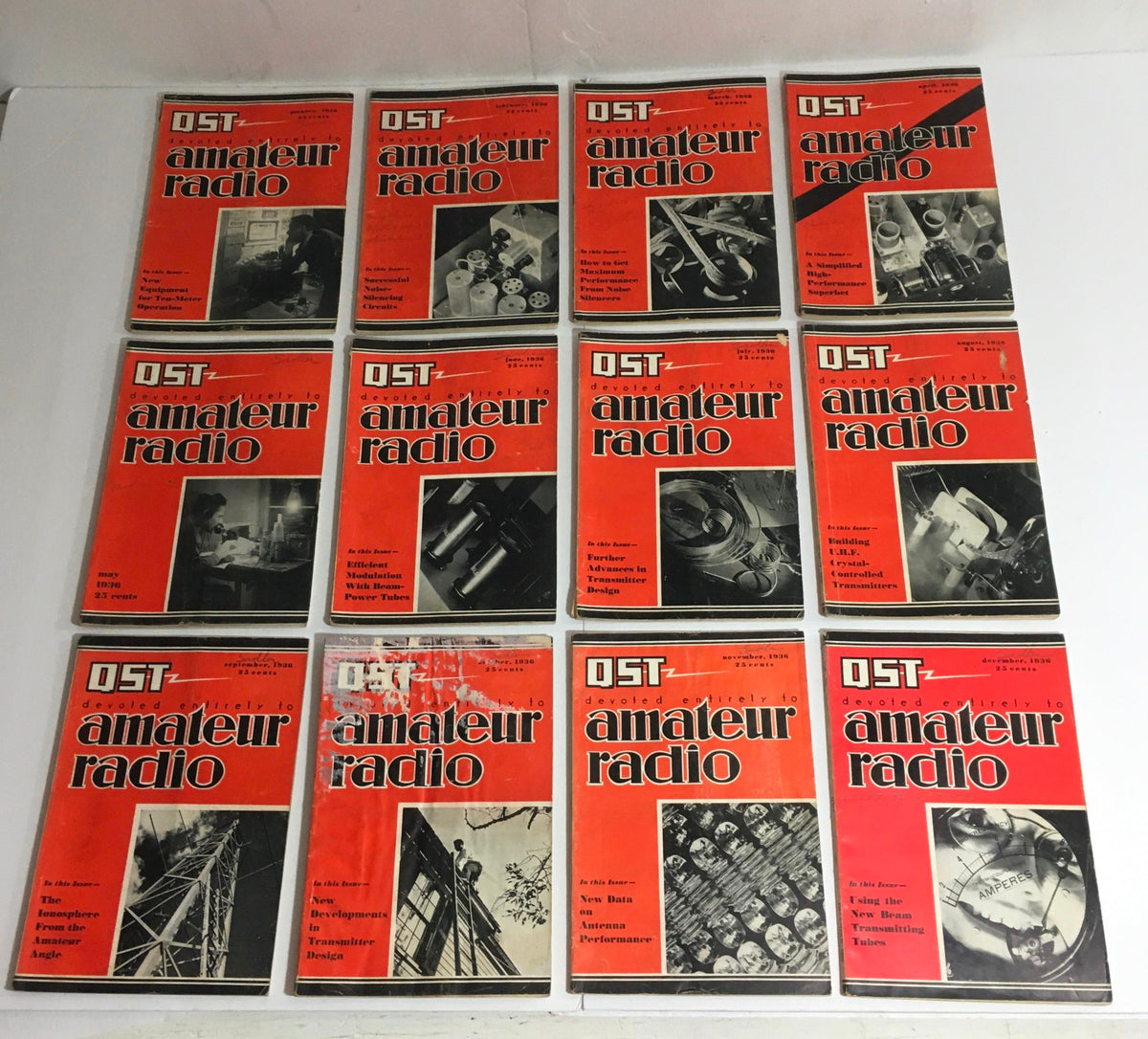 Lot of 12 Complete January to December 1936 QST Amateur Radio magazines displayed on a surface, showcasing the cover designs and vintage aesthetics.