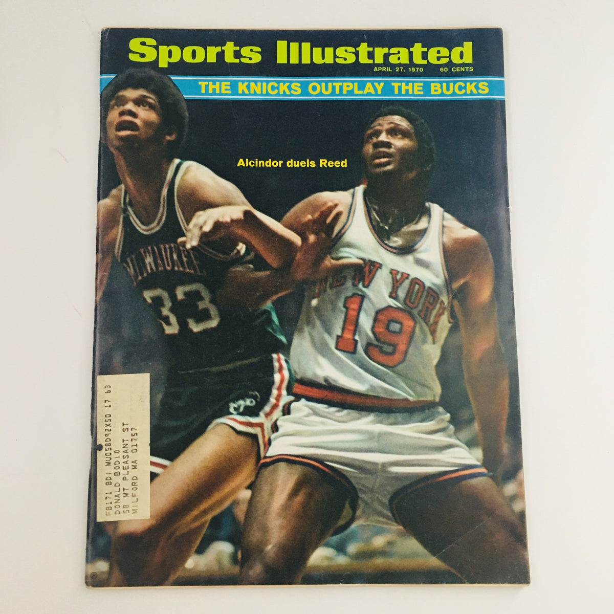 Sports Illustrated Magazine cover from April 27, 1970, featuring Kareem Abdul-Jabbar in a Milwaukee Bucks jersey and Willis Reed in a New York Knicks jersey, showcasing a historic match between the teams.