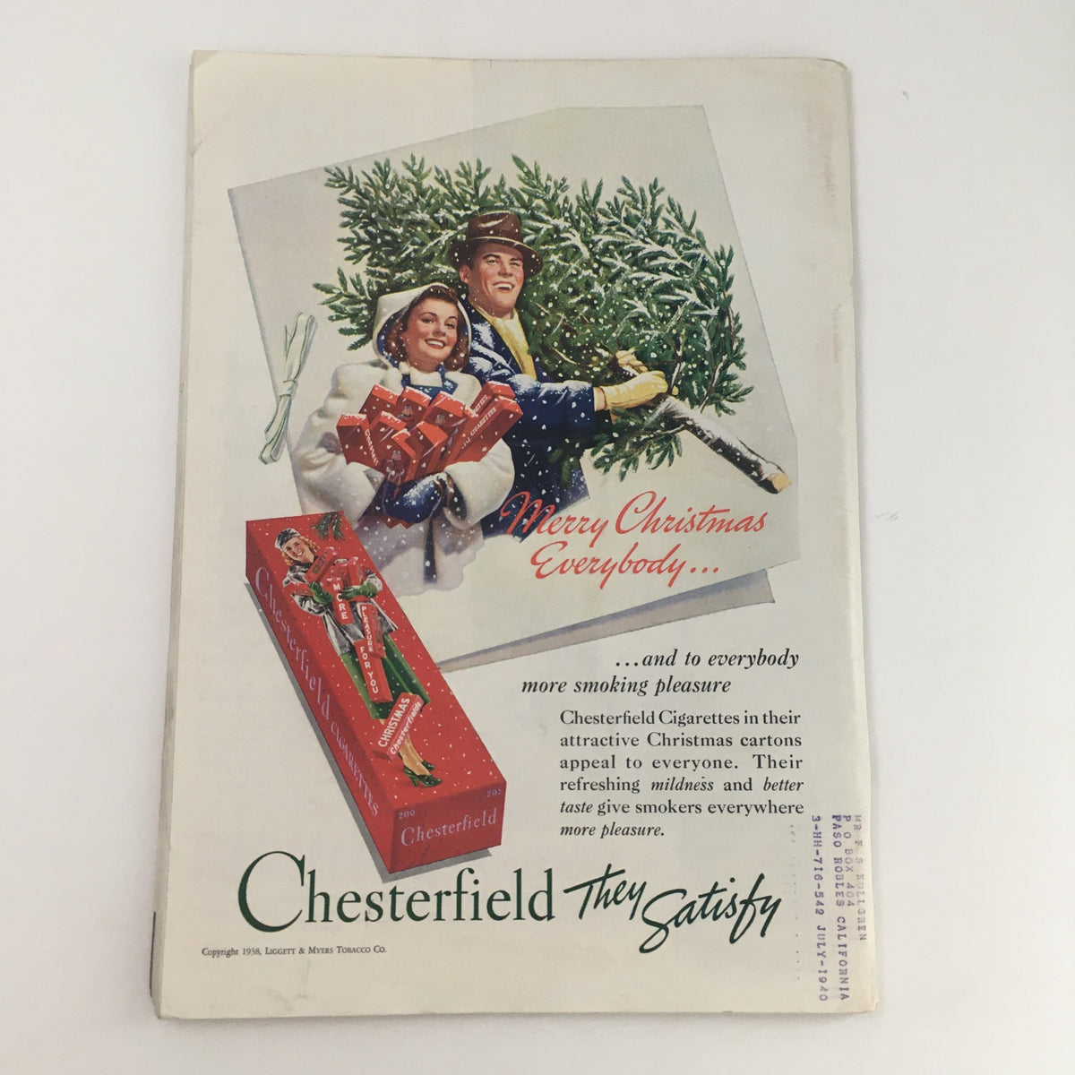 Vintage Chesterfield cigarette advertisement from 1954, depicting a festive holiday scene with a couple amidst a snowy backdrop, promoting their Christmas cartons.