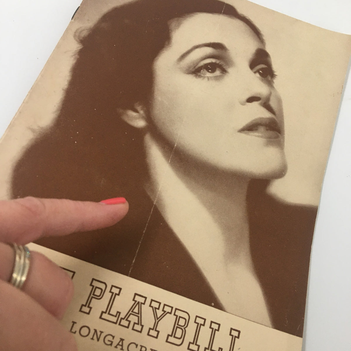 Close-up of the 1941 Playbill for Johnny Belinda, highlighting Helen Craig's portrait, with a hand pointing to the cover, emphasizing the vintage appeal.