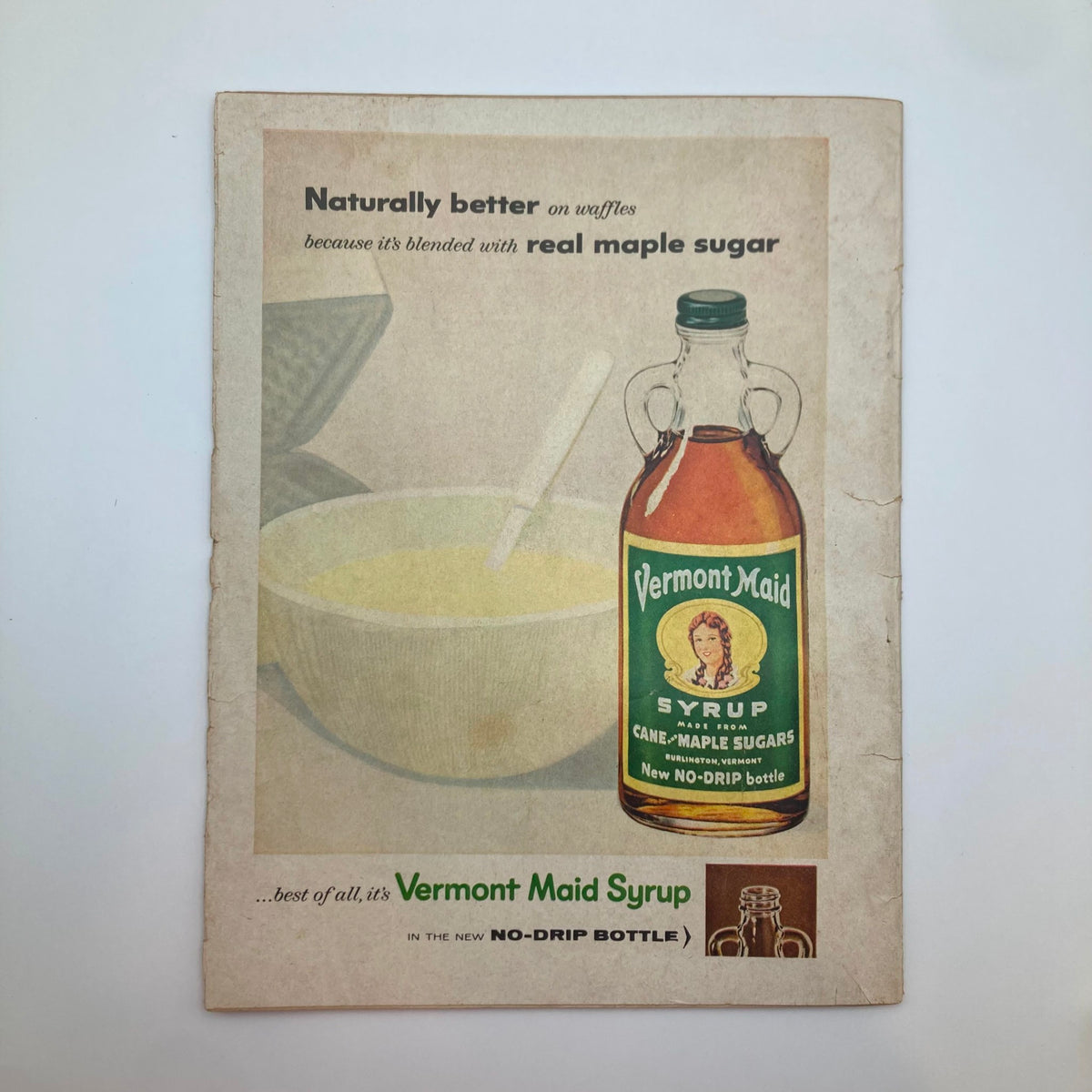 Cover of Vermont Maid Syrup advertisement featuring a glass bottle and a bowl, highlighting its use with waffles, from a vintage magazine.