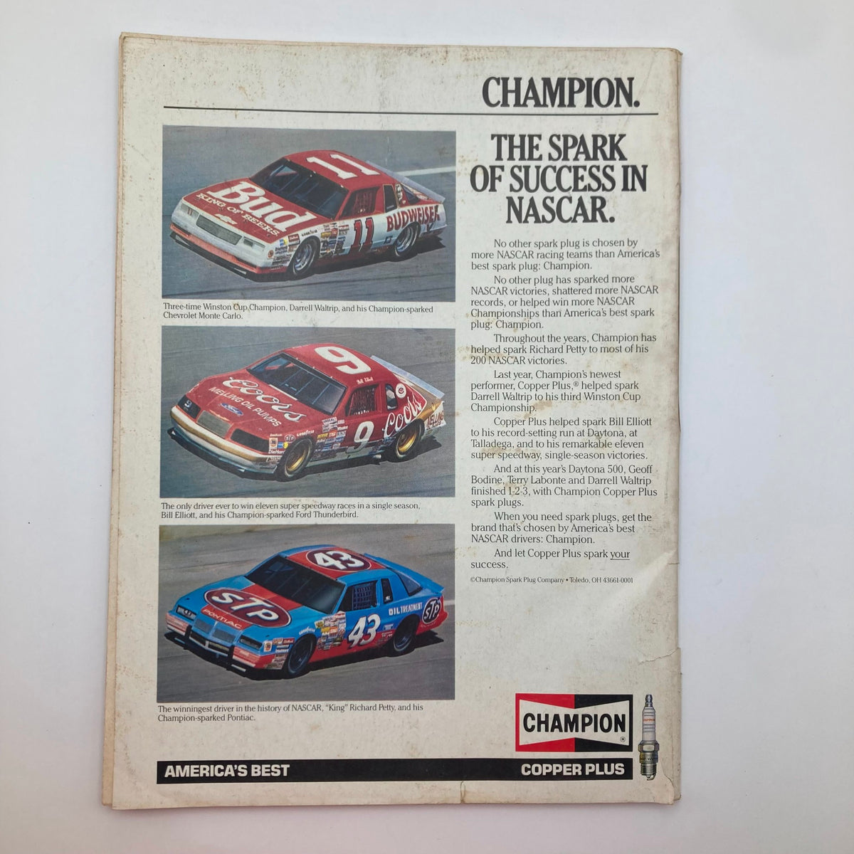 Back cover of the VTG Stock Car Racing Magazine September 1986 featuring a Champion Spark Plug advertisement showcasing iconic NASCAR race cars. Highlighted cars include Darrell Waltrip's Chevrolet Monte Carlo and Bill Elliott's Ford Thunderbird, reflecting the excitement of 1980s stock car racing.