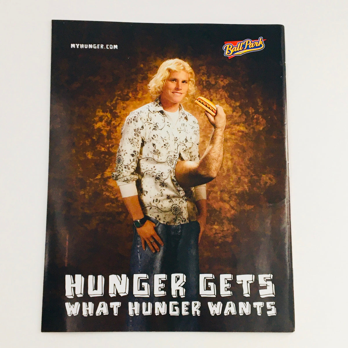Advertisement featuring a model with a playful expression holding a hot dog, with the text 'Hunger Gets What Hunger Wants', showcasing food culture humor.