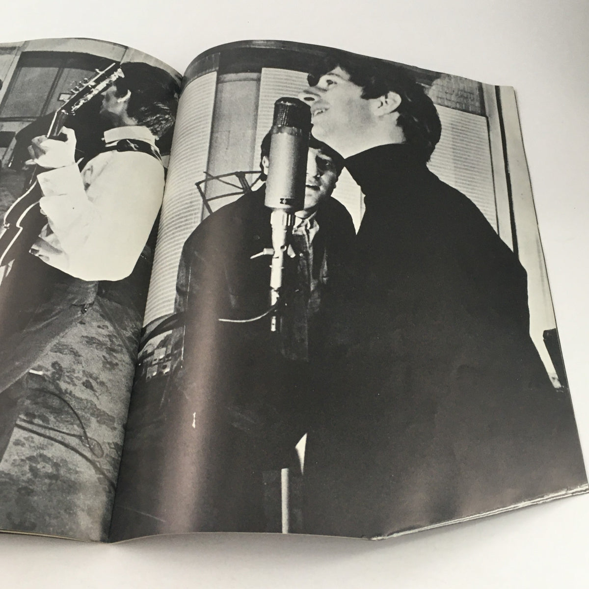Black and white photograph from the 1964 magazine featuring The Beatles, showing band members performing and singing into a microphone, illustrating their musical energy.