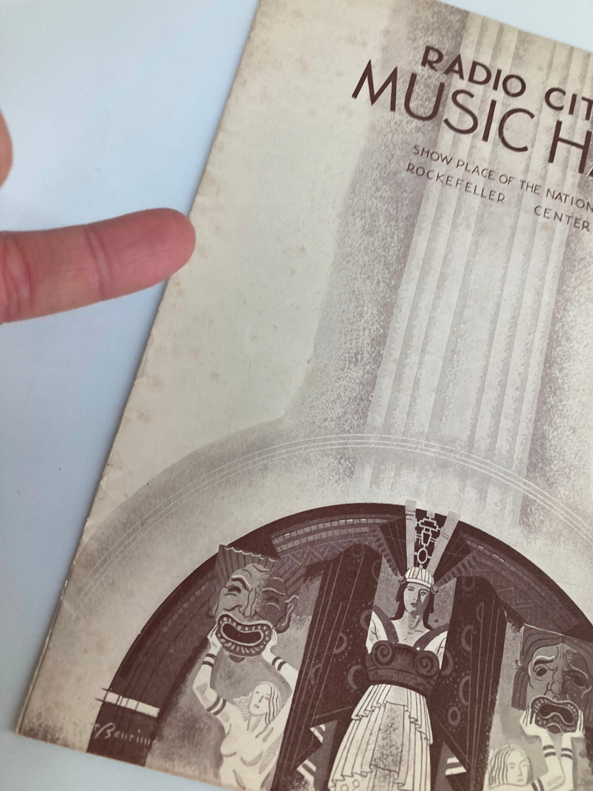 Close-up of the cover of the 1936 Radio City Music Hall Weekly, featuring the title and intricately illustrated characters, highlighting the vintage aesthetic.