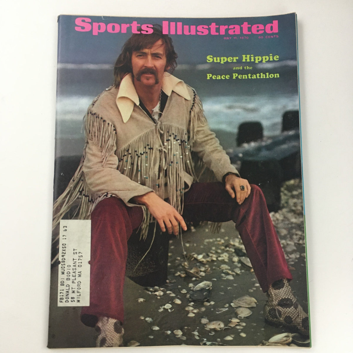 Cover of Sports Illustrated Magazine May 11 1970 featuring the article 'Super Hippie and the Peace Penthalon'. The magazine showcases a man with long hair wearing a fringed jacket, sitting on a rocky beach.