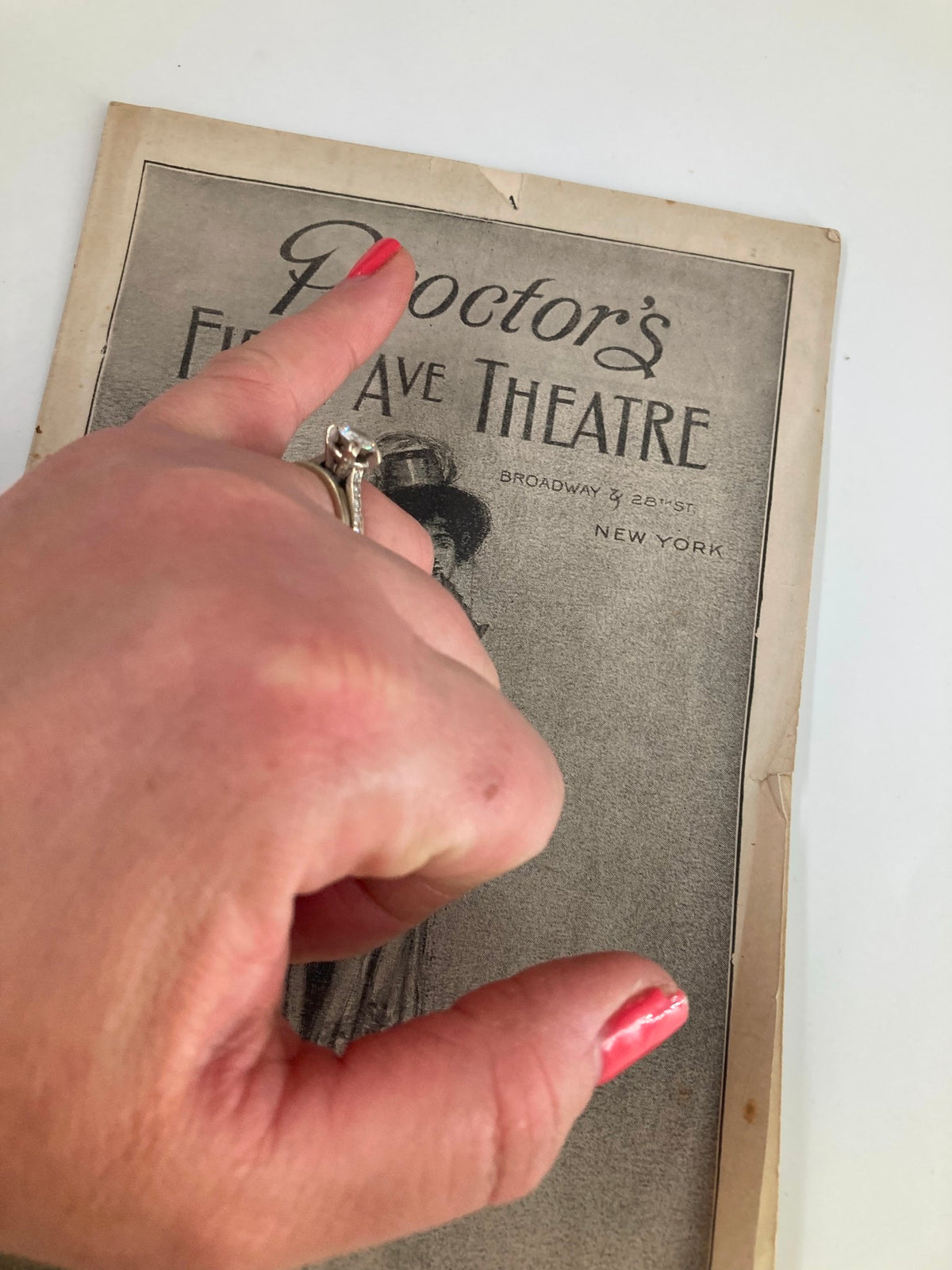 Close-up of a hand pointing at the cover of the 1913 Proctor's Fifth Avenue Theatre, showcasing the detailed artwork and vintage appeal relevant to Hunter's Twin Statue Dogs.