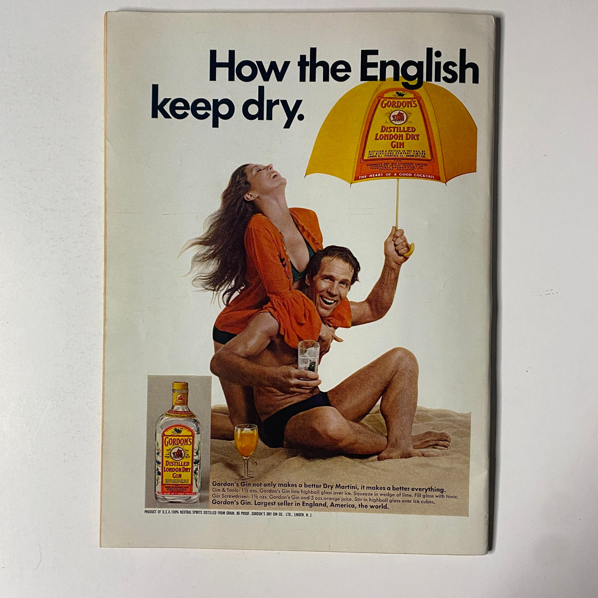 Advertisement from The New Yorker Full Magazine July 12, 1976 for Gordon's Gin, featuring a beach scene with a man and woman enjoying drinks under an umbrella.