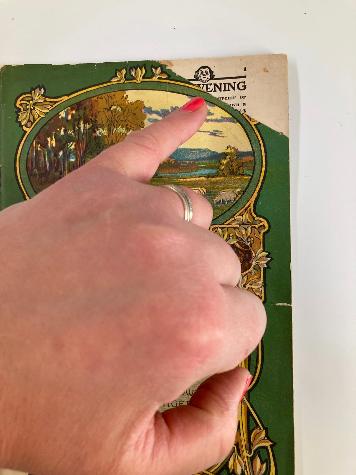 Detail of the 1913 New Amsterdam Theatre Playbill showing a hand pointing at the top of the cover, highlighting the vintage design and title 'New Amsterdam Theatre'.