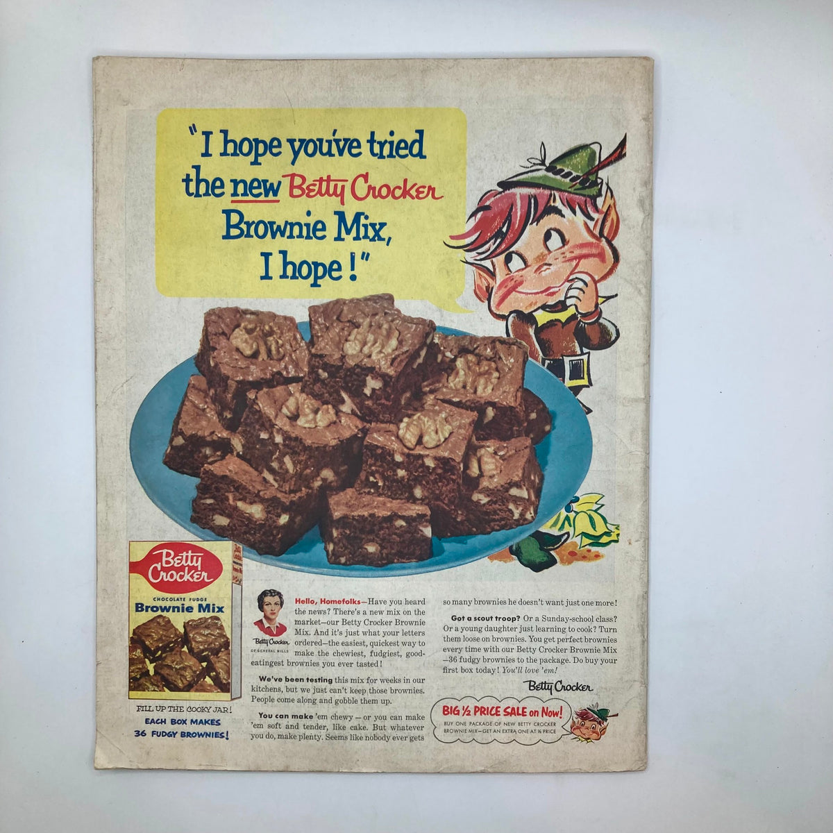 Vintage advertisement for Betty Crocker Brownie Mix featuring a playful character and a plate of fudgy brownies. The ad includes the text 'I hope you've tried the new Betty Crocker Brownie Mix, I hope!' highlighting the product in a nostalgic 1950s style.