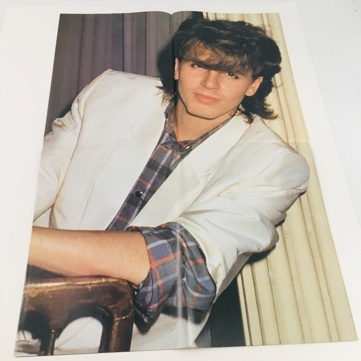 Inside page of Pop Gallery Poster Magazine #12 showcasing a close-up of a male musician with long hair, wearing a white jacket over a plaid shirt, against a backdrop of curtains. This vintage magazine captures the essence of the 1980s pop culture.