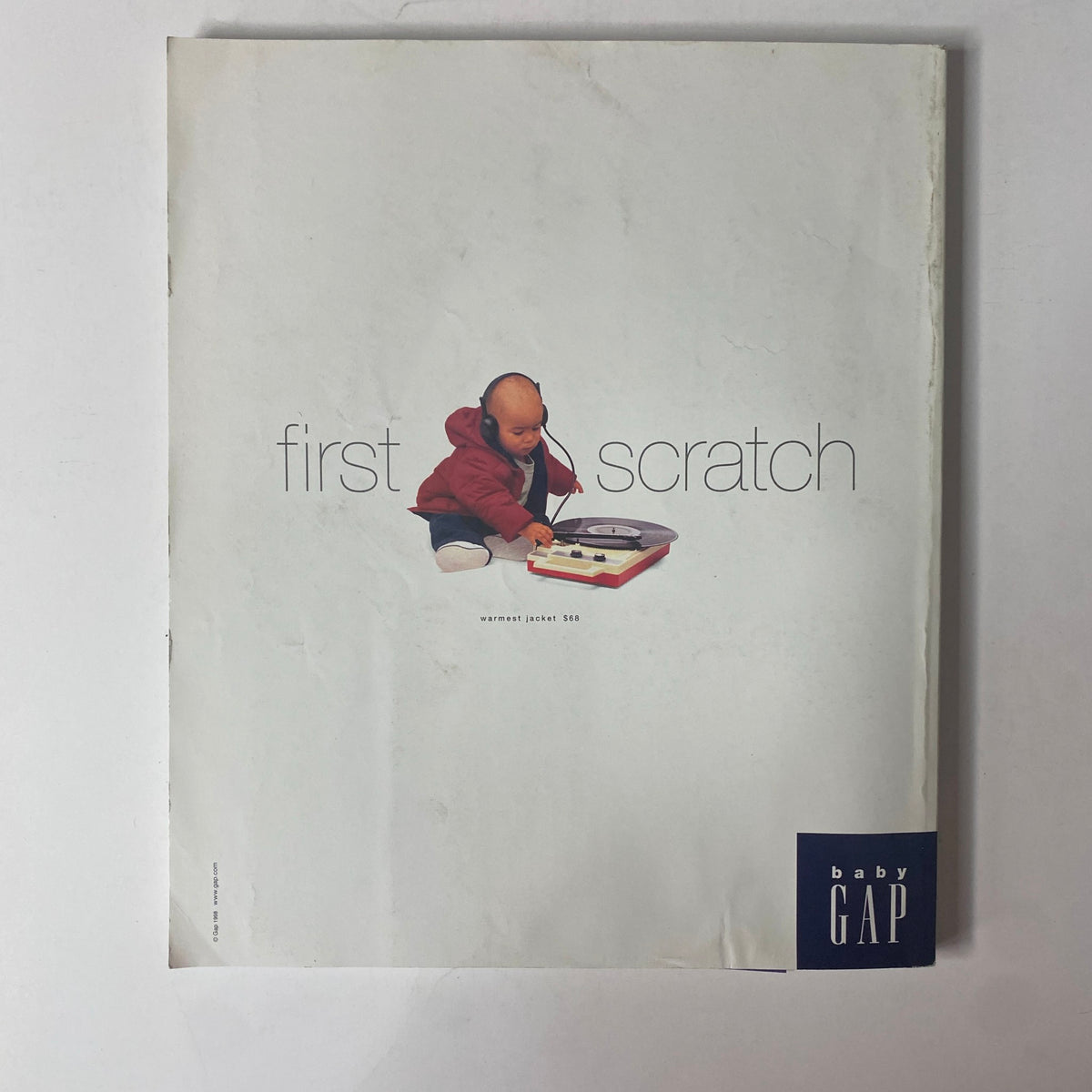 Adorable baby with headphones playing with a record player, featured on the cover of Baby Gap's creative advertisement, invoking a sense of nostalgia.