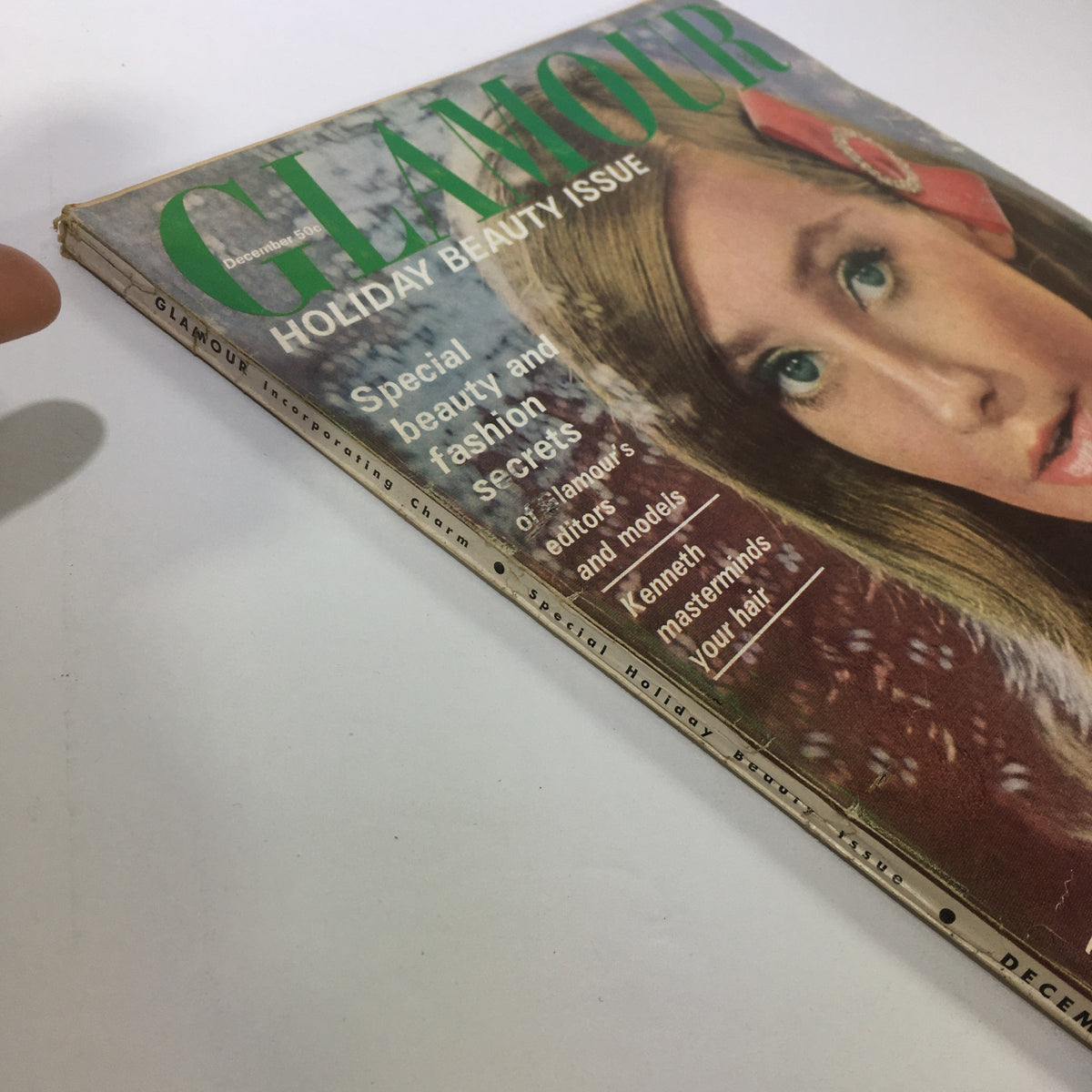 Side view of VTG Glamour Magazine: December 1964 - Holiday Beauty Issue, revealing details of the magazine's design and special features related to beauty and fashion.
