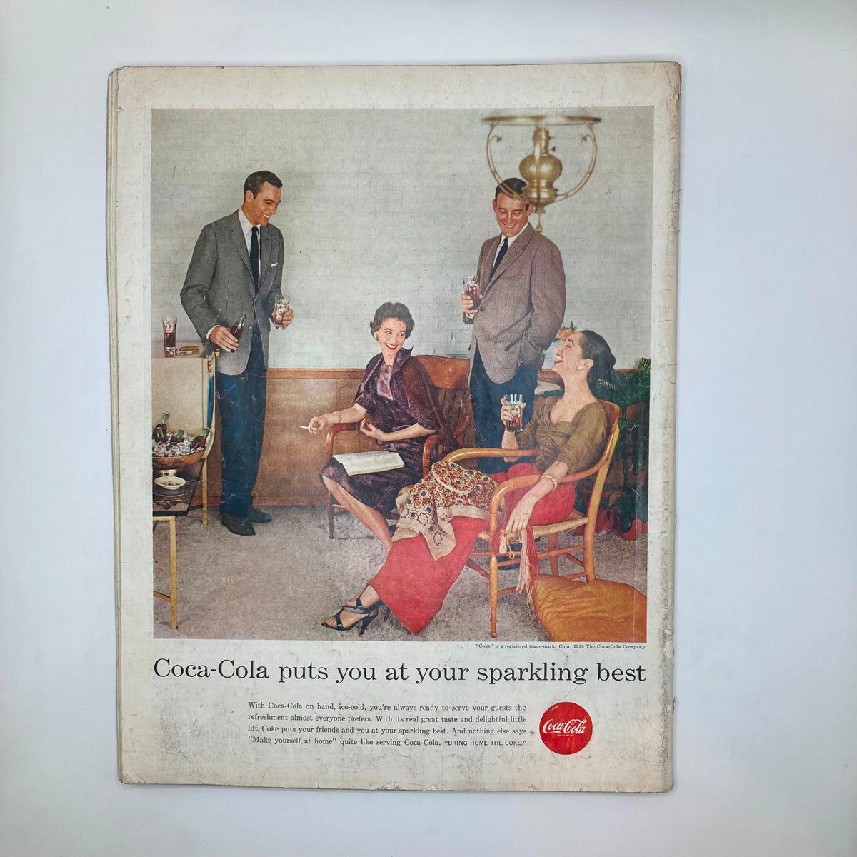 Back cover of the Saturday Evening Post magazine dated October 27, 1956, featuring a Coca-Cola advertisement with an elegant gathering of well-dressed adults enjoying refreshments.