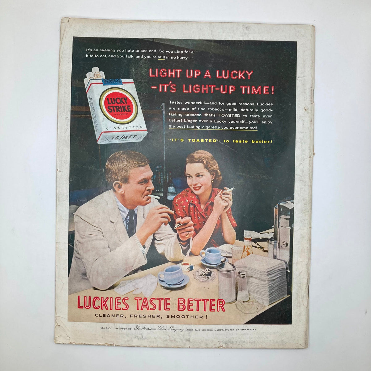 Back cover of Saturday Evening Post Magazine August 18, 1956 displaying a vintage advertisement for Lucky Strike cigarettes, featuring a man and woman at a cafe.
