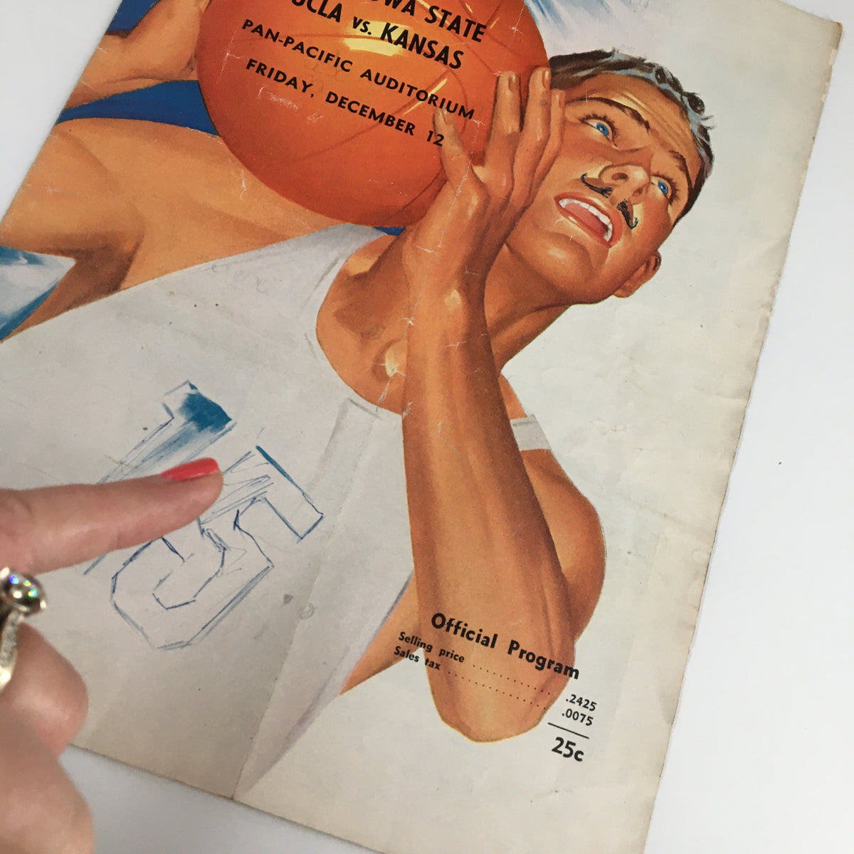 Close-up of the official program cover for the December 12, 1960 NCAA Basketball game between UCLA and Kansas, highlighting the player's jersey number and expressive illustration.