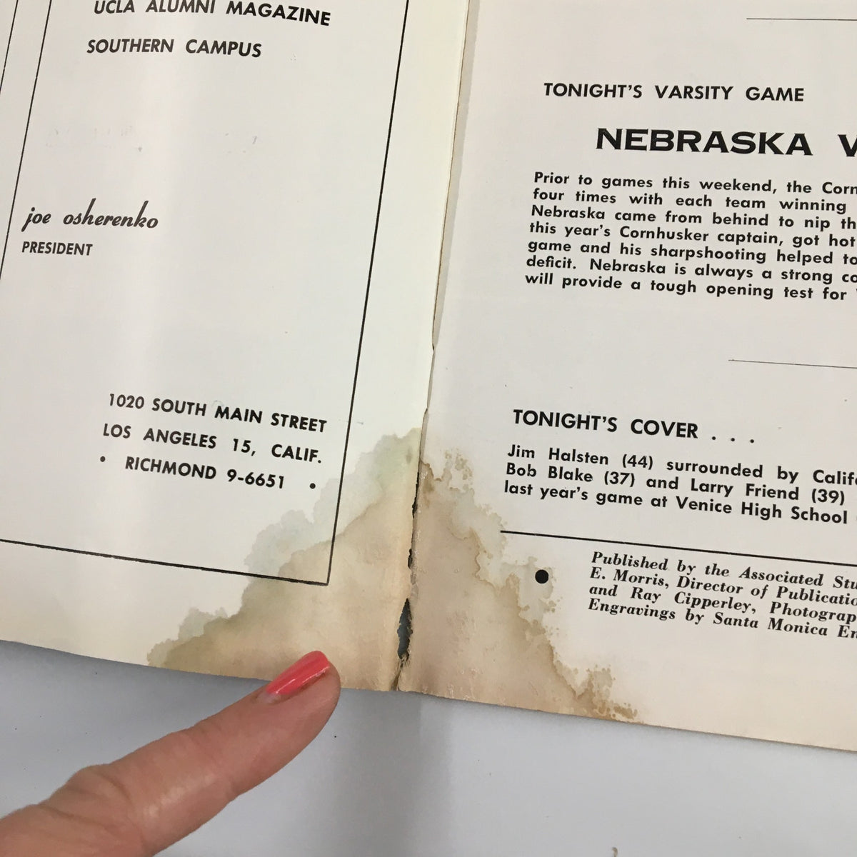 Interior page of the official program from December 1, 1956 NCAA Basketball game Nebraska vs UCLA. Displays team rosters alongside stains, showcasing the program's age.