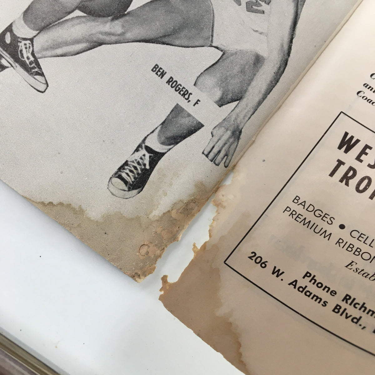 Close-up image of a vintage NCAA Basketball program page from December 1, 1956 featuring Ben Rogers, with noticeable wear including torn edges.