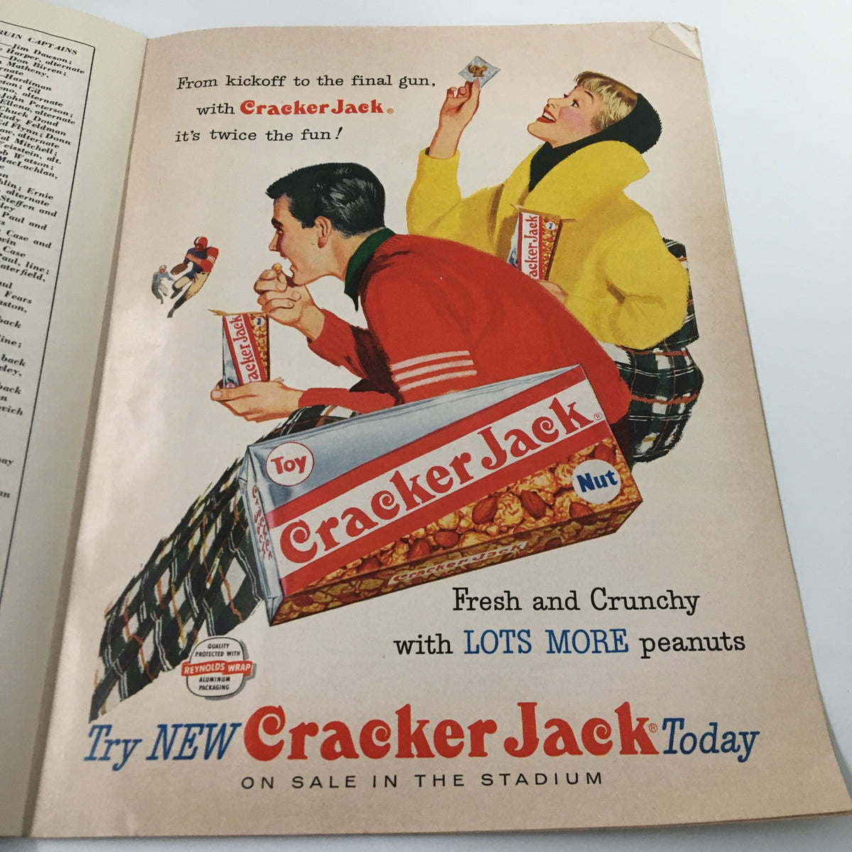 Vintage advertisement for Cracker Jack featuring a playful scene with two individuals enjoying snacks during a football game. September 27 1957 NCAA Football Illinois vs UCLA The Goal Post Official Program.