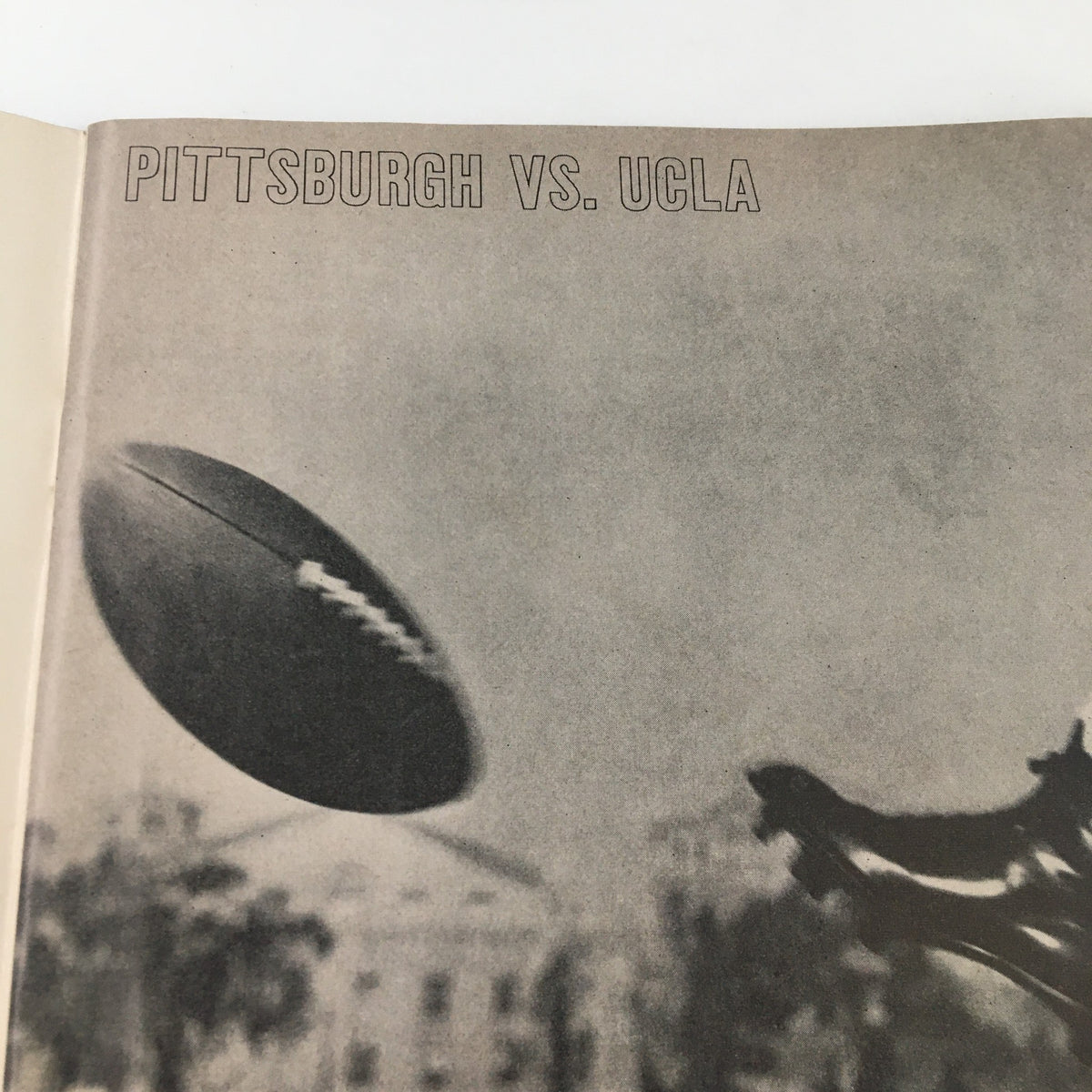 Black and white image from the September 17 1960 NCAA Football Pittsburgh vs UCLA The Goal Post Program showing a football in mid-air with players in the background.