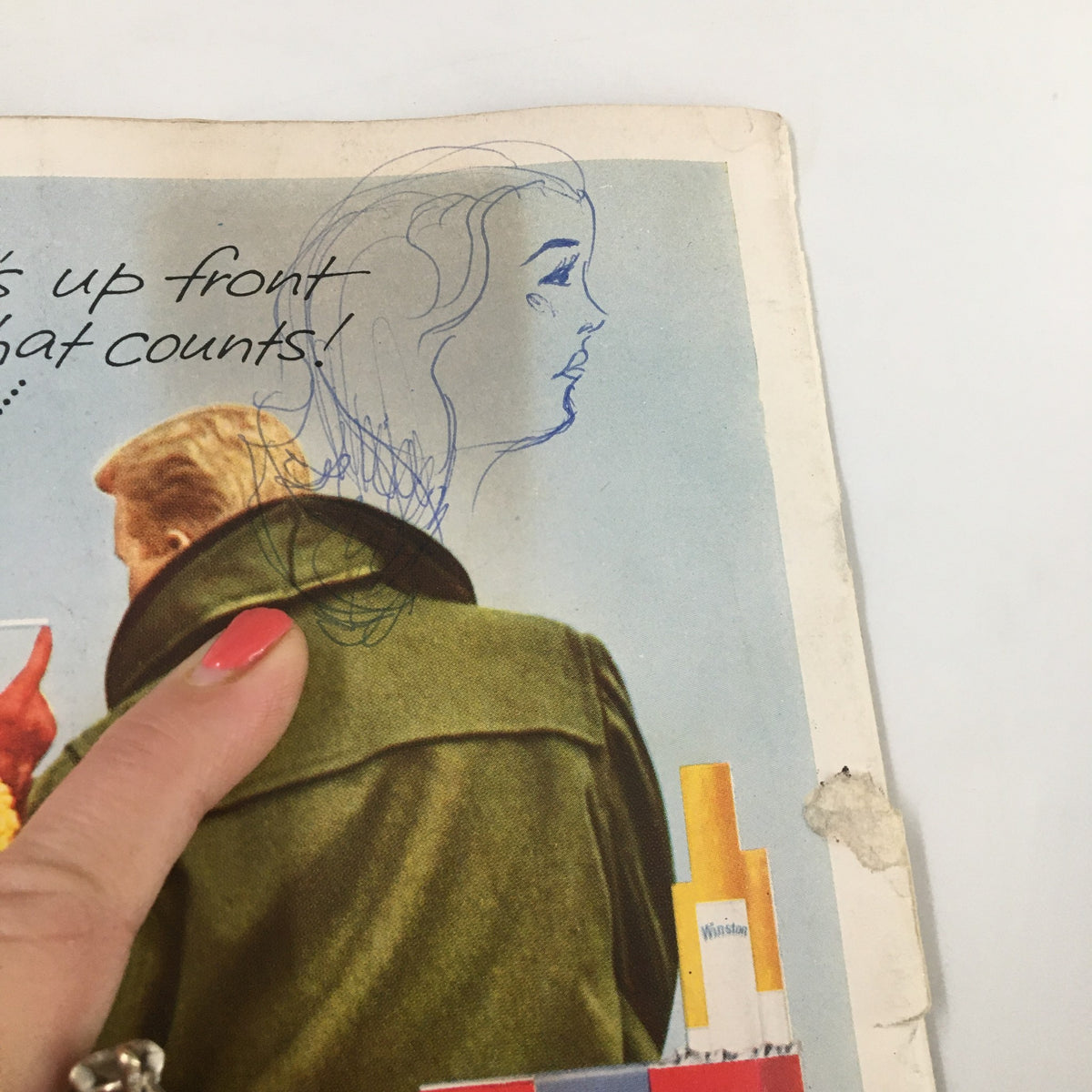 Close-up of an advertisement from October 17 1959 NCAA Football featuring a woman and a man discussing Winston cigarettes, highlighting vintage marketing and social norms of the time.