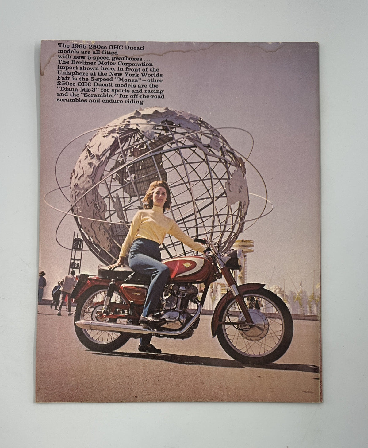 Cycle Magazine August 1964 cover featuring a woman posing on a 1965 Ducati motorcycle in front of the Unisphere at the New York World's Fair, showcasing the magazine's focus on vintage motorcycle insights.