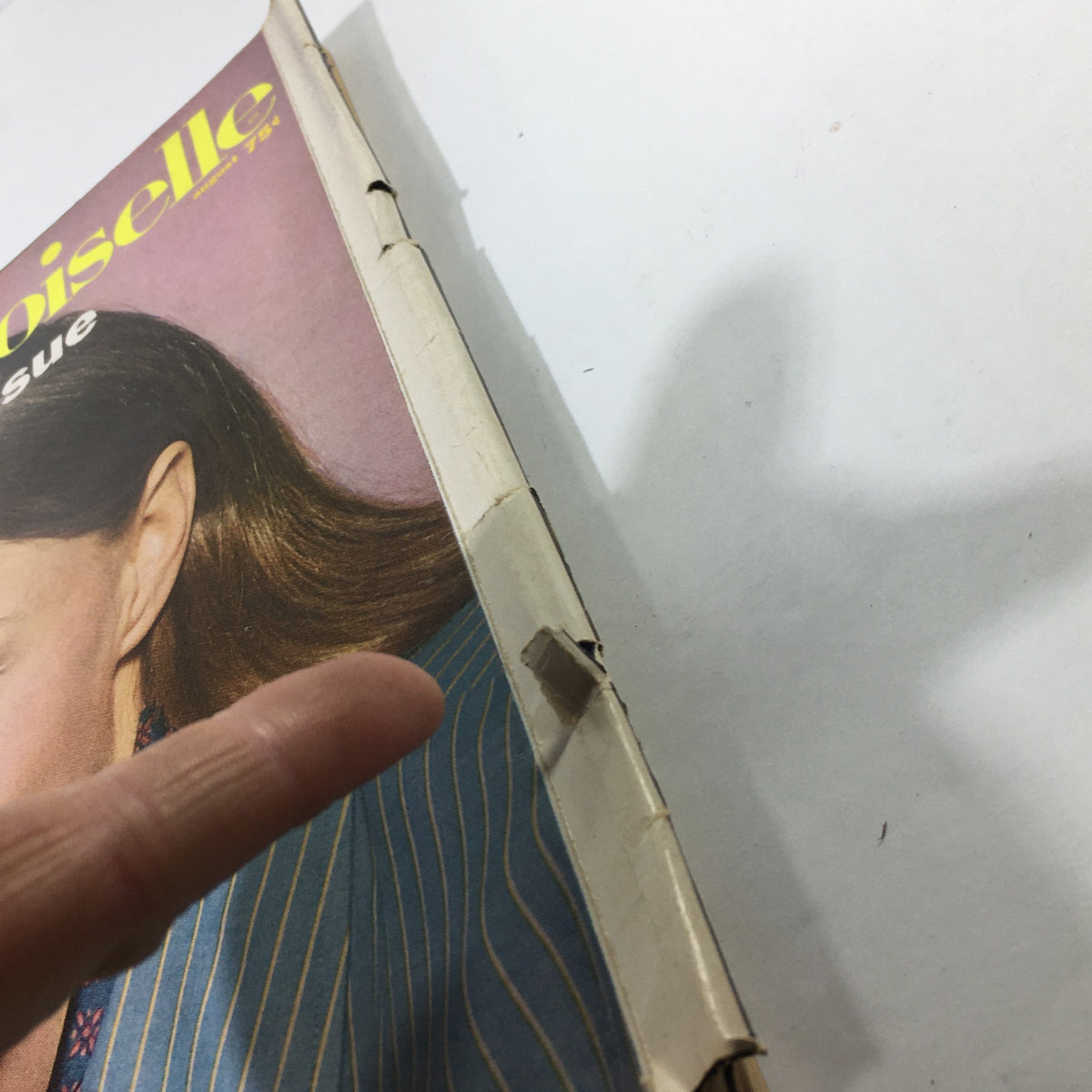 Side view of the worn spine of VTG Mademoiselle Magazine: April 1967 - The College Issue, highlighting the magazine's vintage condition with visible edges and minor damages.