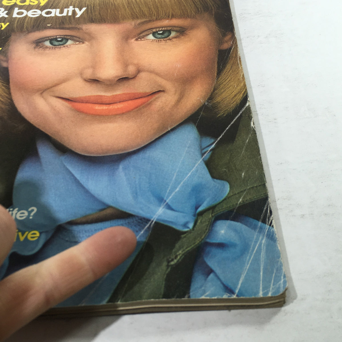 Close-up view of the vintage March 1975 Mademoiselle Magazine cover featuring a smiling model with blue eyes and a bright orange lipstick, showcasing 1970s fashion.