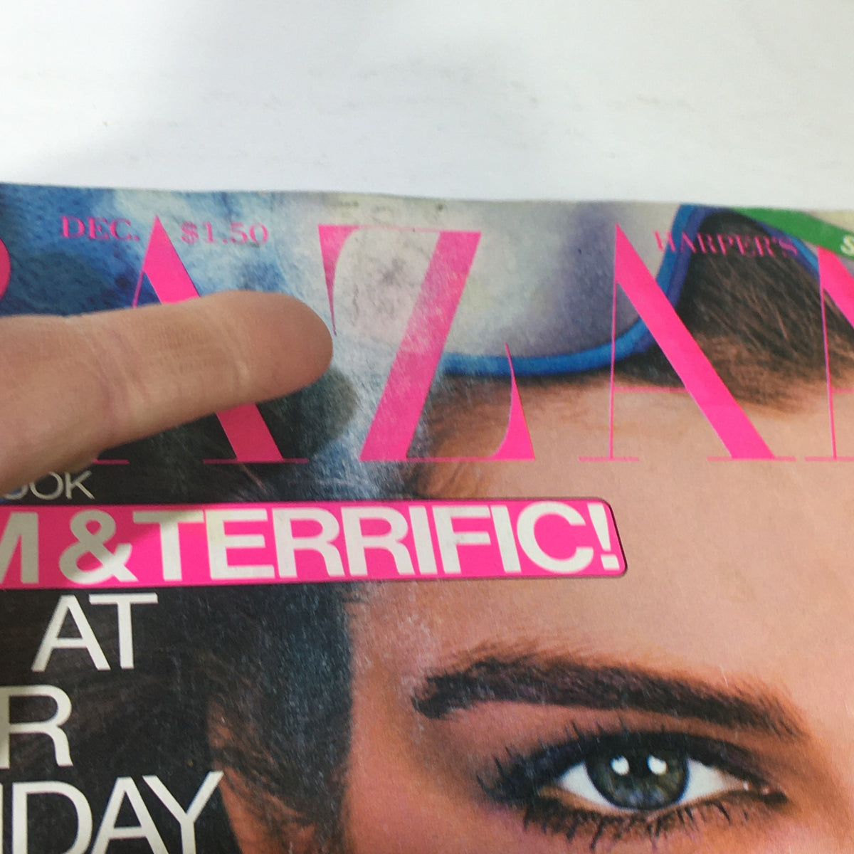 Close-up of VTG Bazaar Magazine: December 1980 cover showing model's eye and text highlighting holiday beauty and fashion tips. Includes a finger pointing at the magazine title, indicating condition.