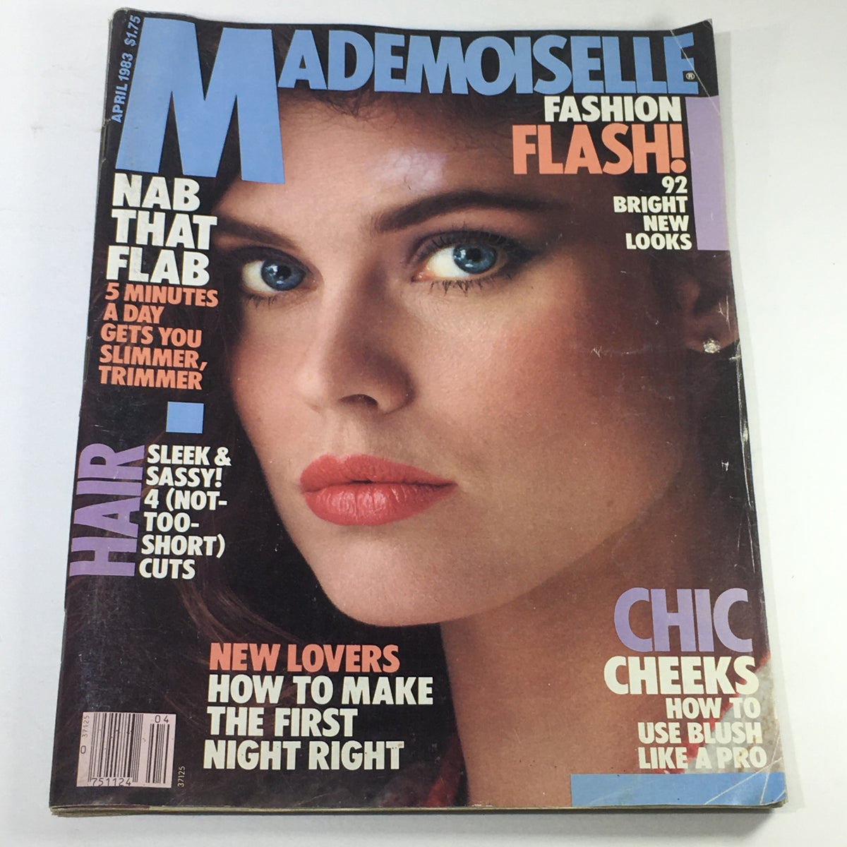 VTG Mademoiselle Magazine: April 1983 featuring a close-up of a model's face with striking blue eyes and vibrant red lips, showcasing 1980s fashion and beauty trends.