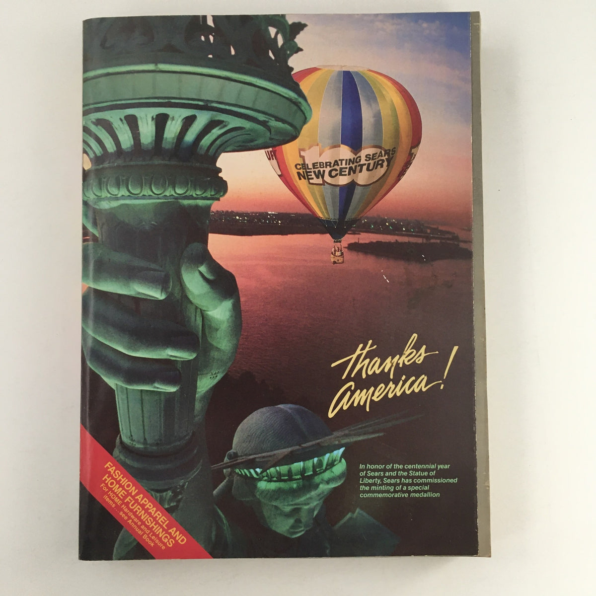 Sears Fashion Apparel Sears Centennial 1976 Celebrating Sears catalog cover featuring a hot air balloon against a sunset view with the Statue of Liberty's arm in the foreground, captioned 'Thanks America!'.