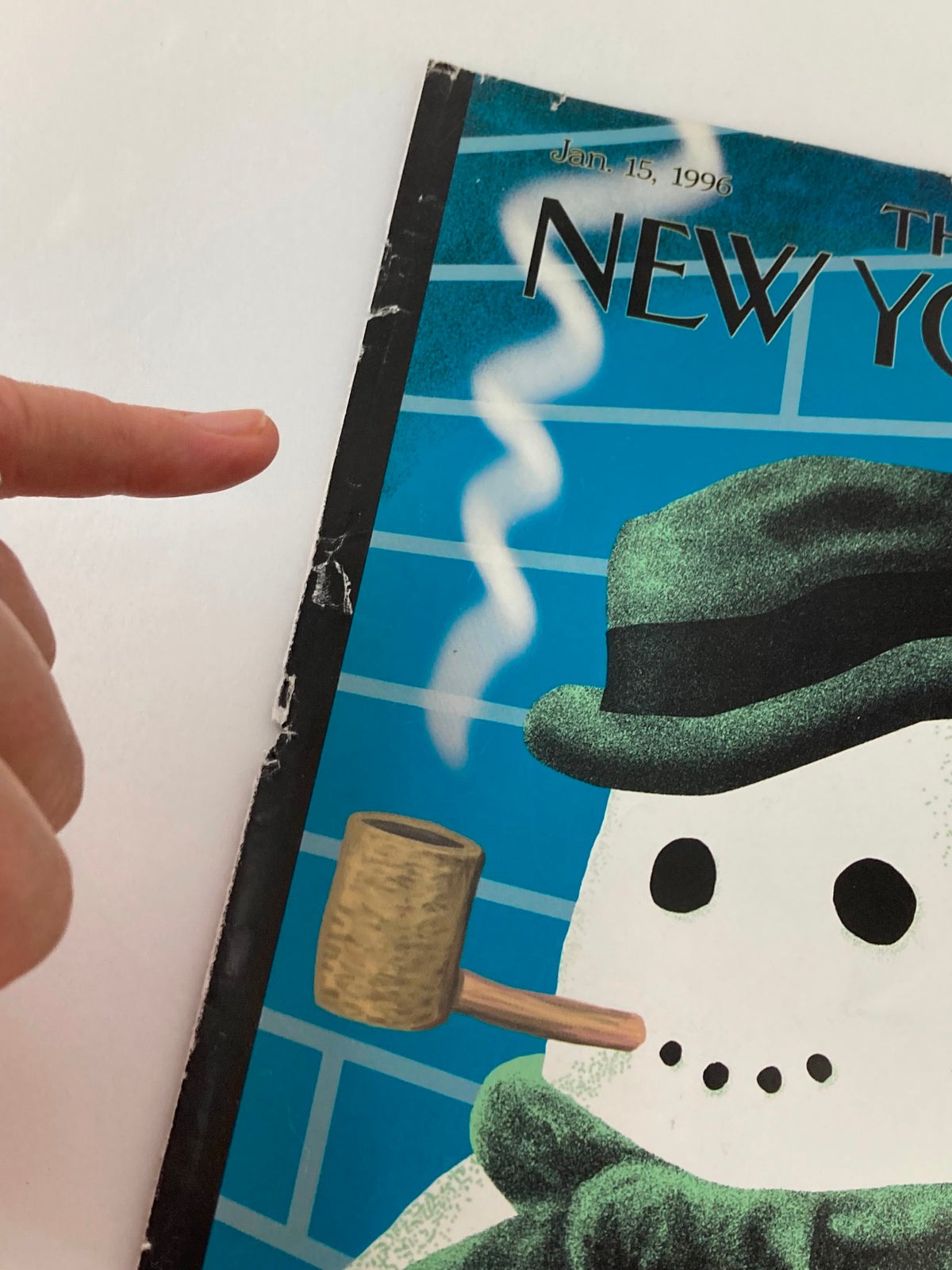 Close-up detail of The New Yorker cover from January 15, 1996 titled 'Snow Smoking', highlighting a hand pointing at the snowman with a pipe, showcasing vintage wear.