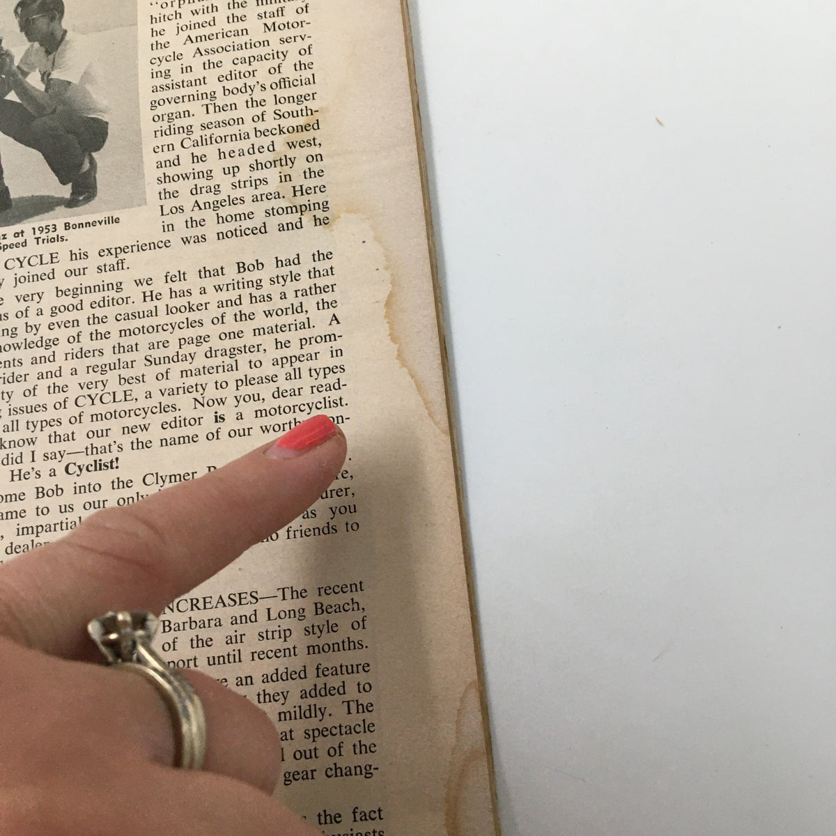 Close-up of a vintage magazine page from VTG Cycle Magazine December 1953 focusing on editorial content, with a highlighted finger pointing to text.