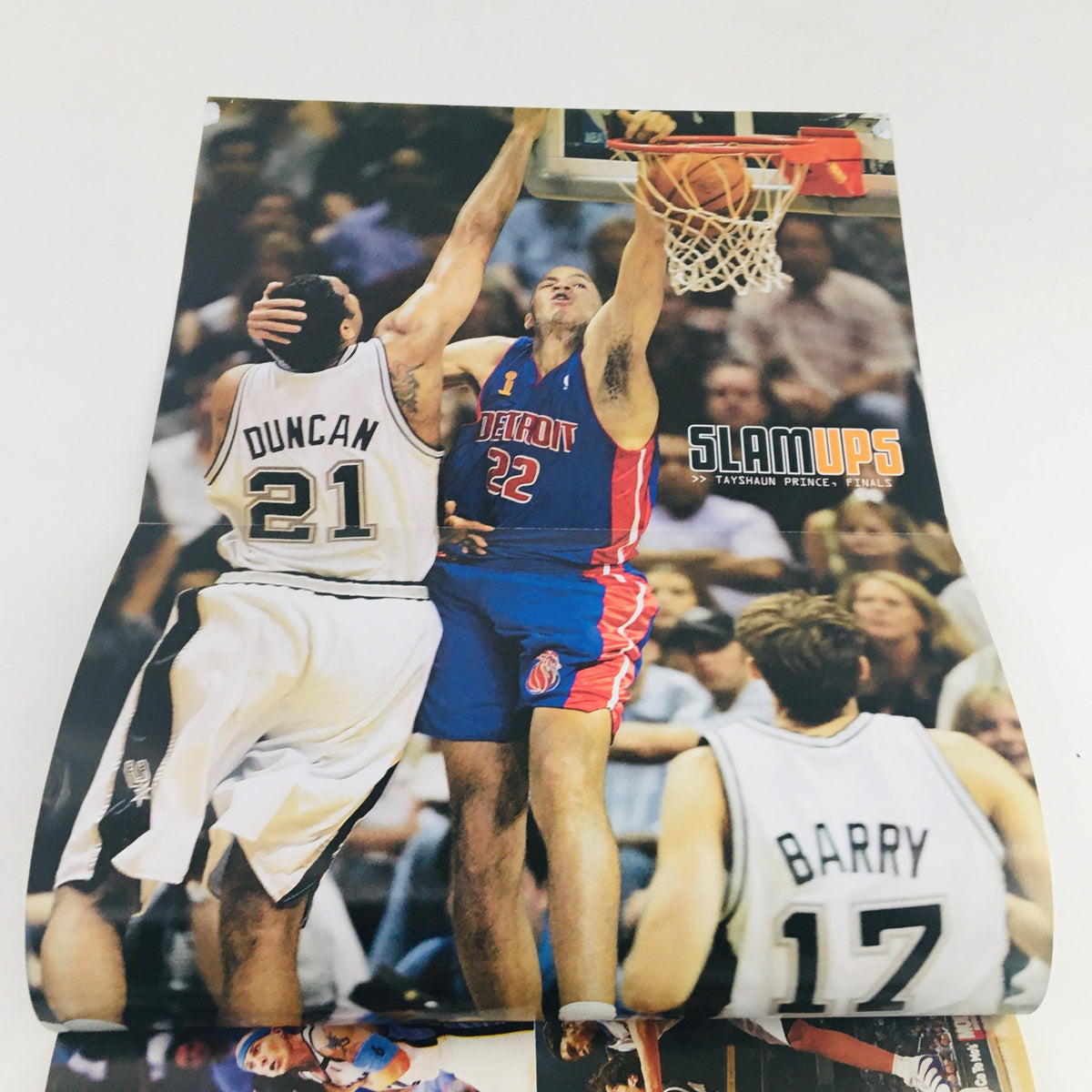 Image from Slam Magazine September 2005 depicting Tim Duncan defending against Detroit Pistons' player Tayshaun Prince, capturing a memorable NBA moment.