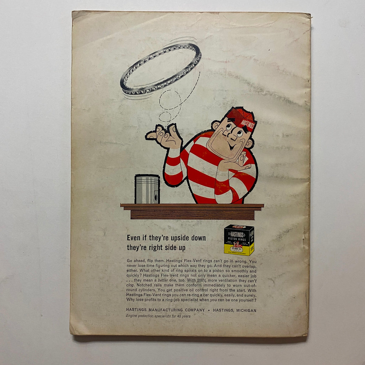 Back cover of VTG Motor Magazine August 1965 featuring a colorful illustration of a man flipping a ring, promoting Hastings Flex-Vent piston rings for automotive applications.