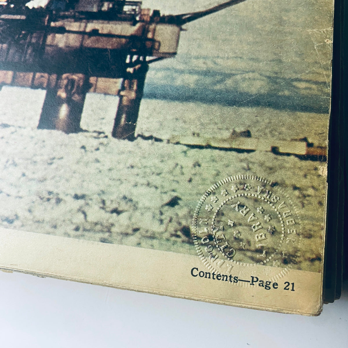 Close-up of a bound magazine page from 'The New York Times Library Edition Bound Magazine 1970 March - April' showcasing a photograph of an oil rig with the stamp 'Property of The Lincoln City Libraries, Lincoln, Nebraska.'.