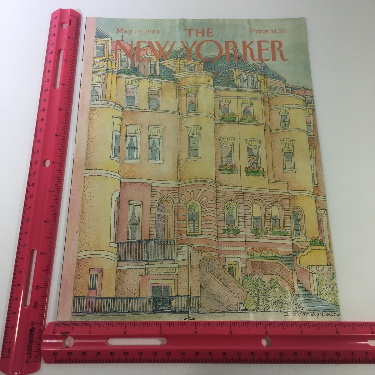 The New Yorker Magazine cover dated May 14, 1984, by Iris Van Rynbach displayed on a flat surface with a ruler for scale, showcasing its vibrant colors and vintage appeal.