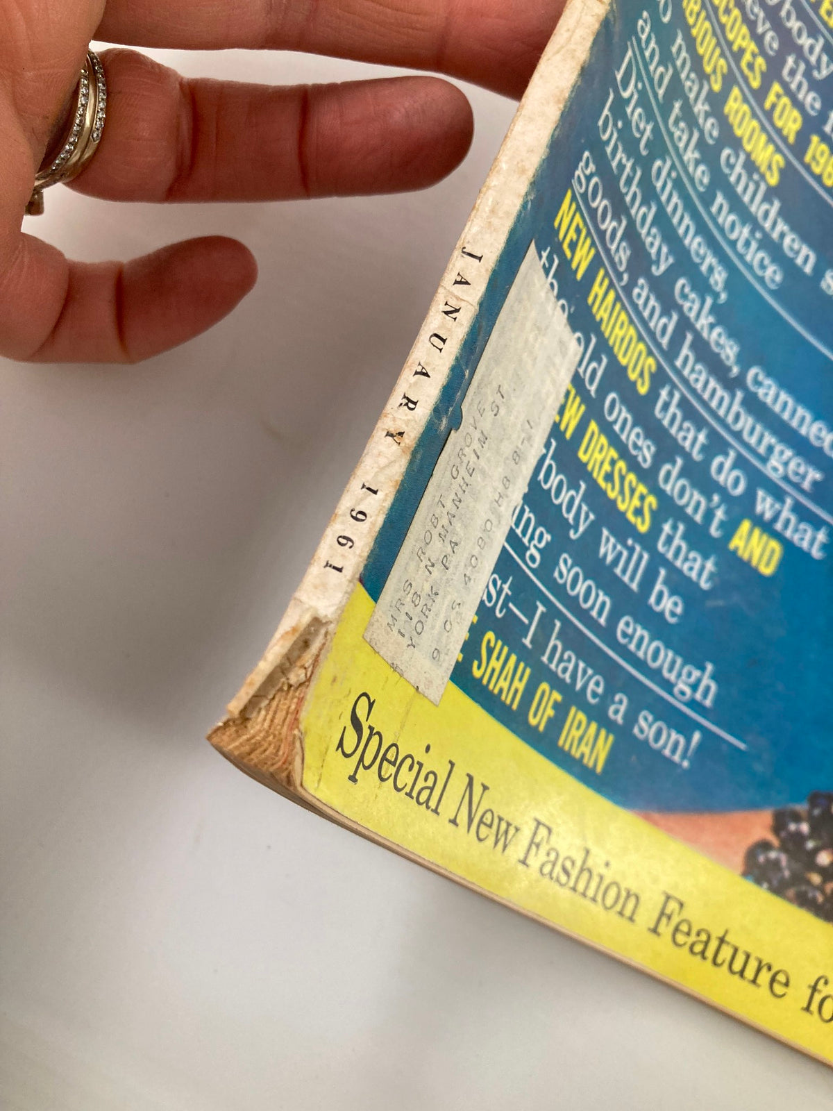 Side view of the spine of VTG McCall's Magazine January 1961 titled 'The Wonderful World of Little Fishes', illustrating magazine details and signs of age with a hand holding the magazine.