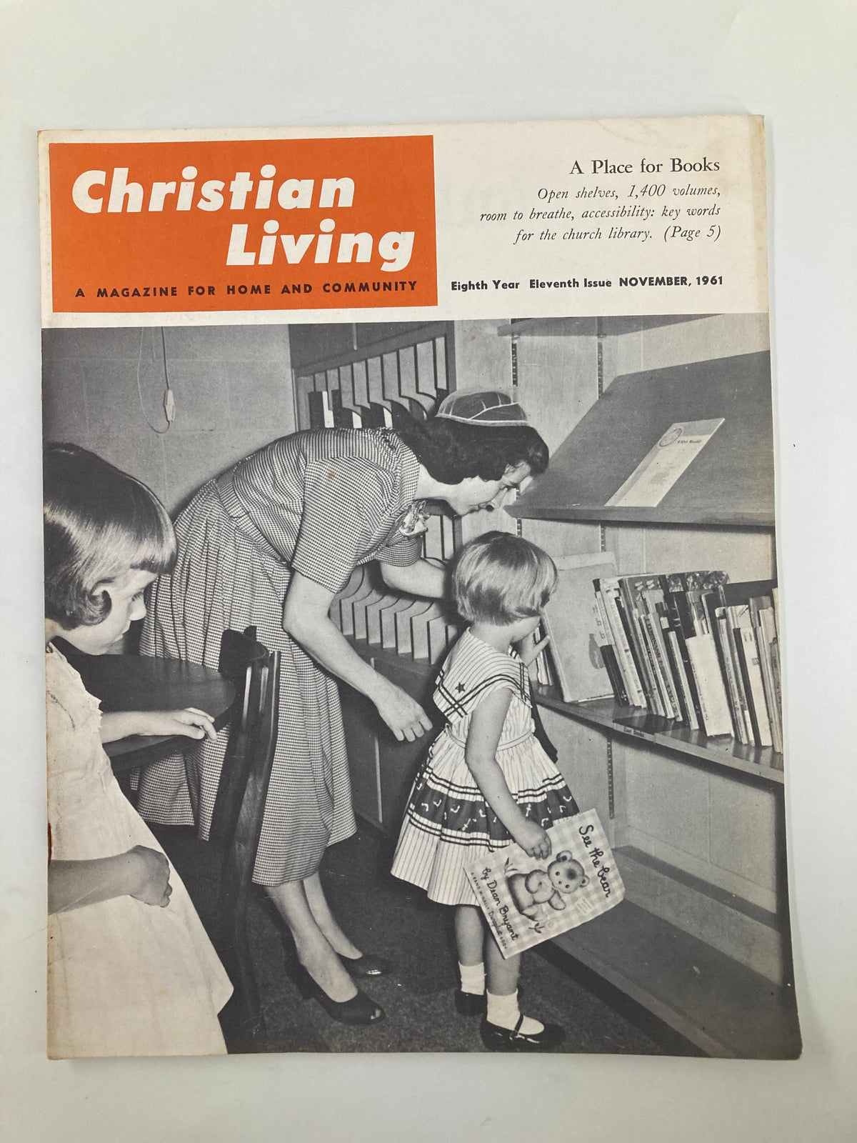 Cover of the VTG Christian Living Magazine November 1961 showcasing a vibrant design and a woman helping children at a bookshelf, highlighting its theme of community and faith.