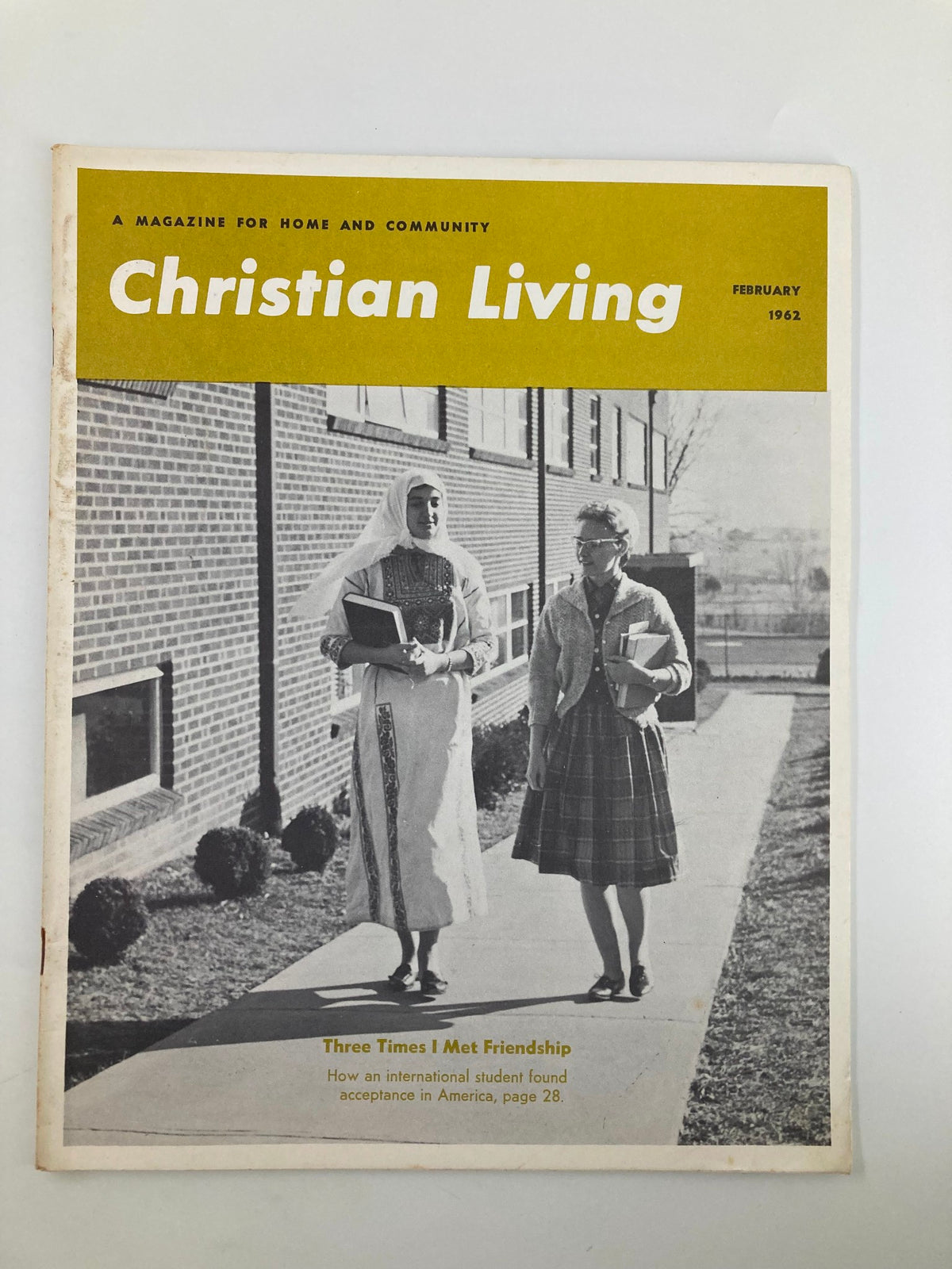 Cover of VTG Christian Living Magazine February 1962 featuring the article 'Three Times I Met Friendship', showcasing two women walking with books outside a building.