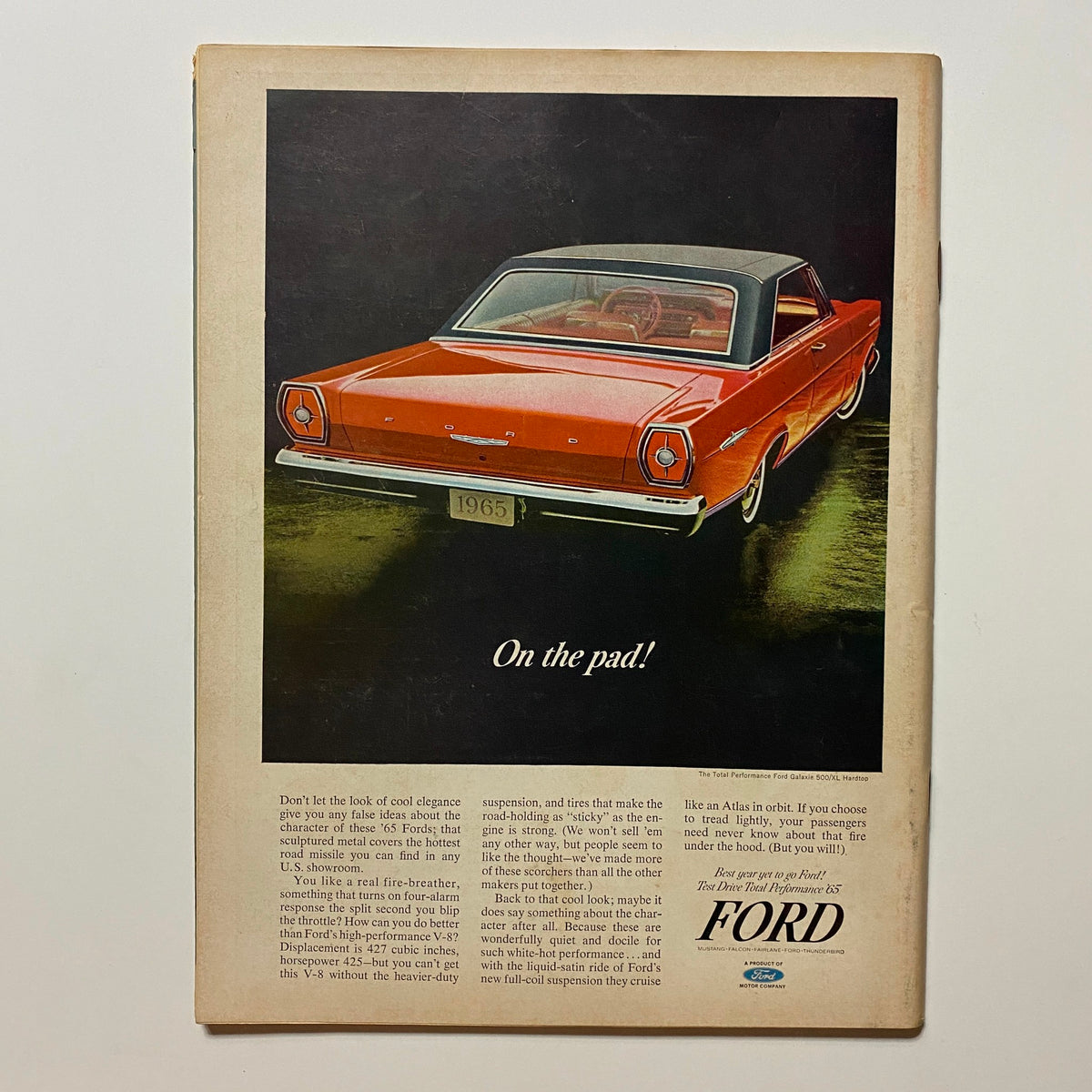 Back cover of VTG Hot Rod Magazine December 1964 featuring a Ford car advertisement with a vibrant orange color and details about performance and handling.